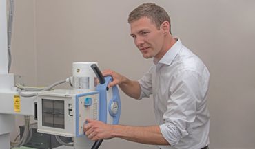 Dr Ryan Hislop moves a X-Ray machine into position.